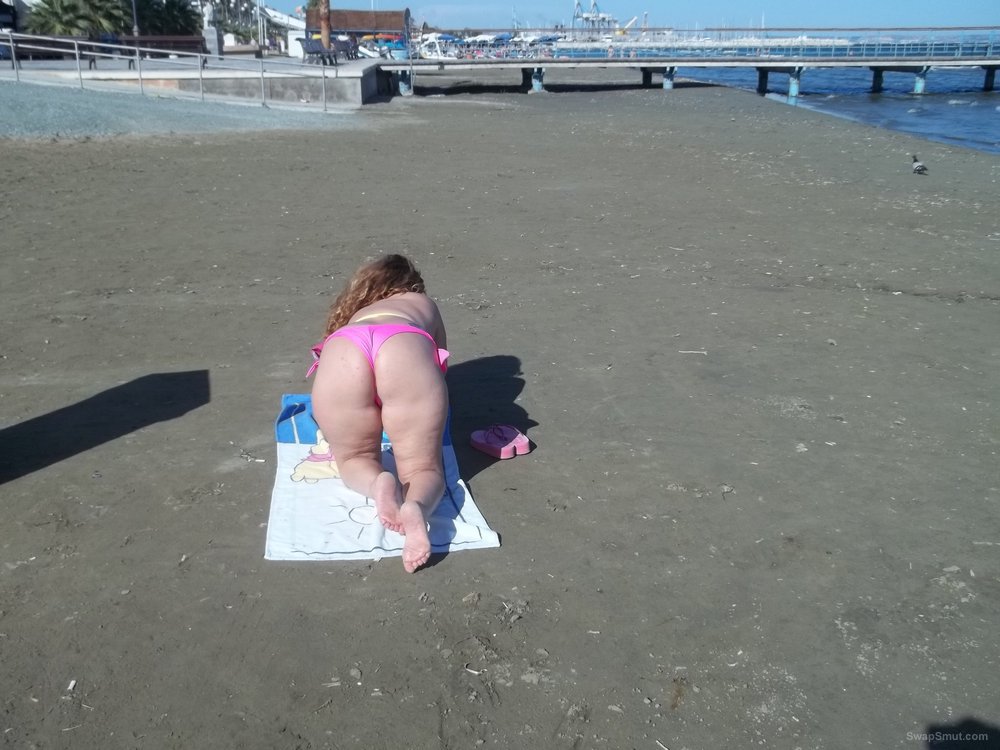 Milf wife resting on the beach in bright pink and yellow bikini
