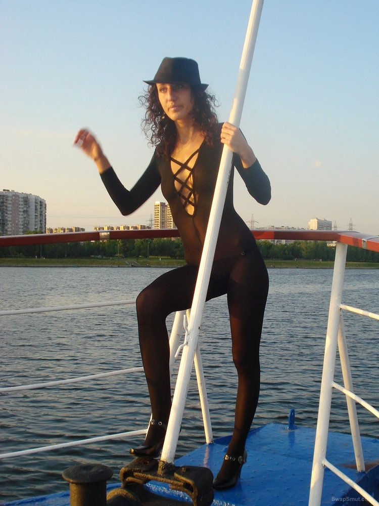 Friends sexy wife posing on a boat while on holiday wearing a catsuit